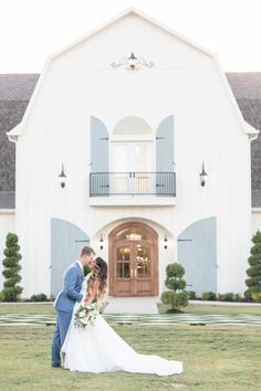 a bride and groom standing in front of a large white building