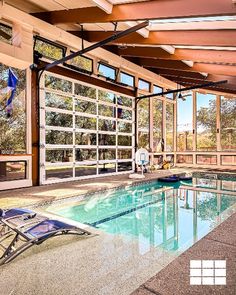 large glass garage door on pool house Pool In Garage, Indoor Pool Ideas Affordable, Sunroom Overlooking Pool, Inside Pool House Ideas, Glass Pool House, Pool House With Glass Garage Doors, Barndominium Indoor Pool, Indoor Pool And Greenhouse