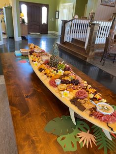 a long boat filled with lots of food on top of a wooden table in a house