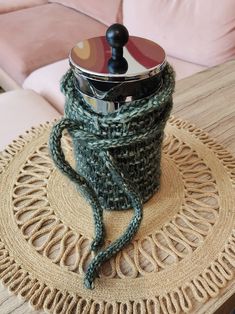 a crocheted coffee cup holder on top of a wooden table