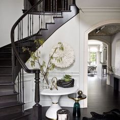 there is a black and white staircase in the house with flowers on the table next to it