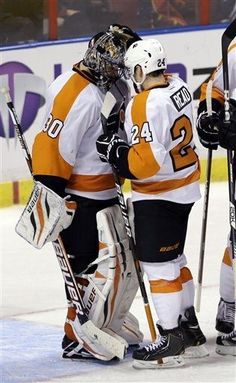 two hockey players standing next to each other with their arms around one another on the ice