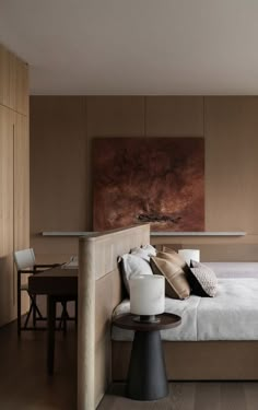 a bedroom with a bed, nightstands and table in front of a painting on the wall