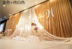 a decorated stage with white drapes and flowers