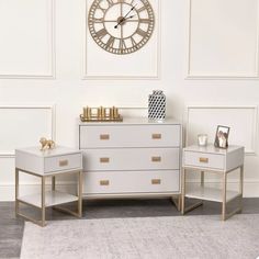 two white dressers with gold handles in front of a large clock on the wall