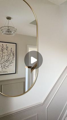 a mirror hanging on the side of a wall next to a stair case with a chandelier