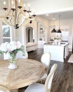 a dining room table with chairs and a vase filled with flowers on top of it