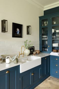 a kitchen with blue cabinets, white counter tops and gold faucets on the sink