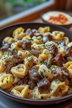 a bowl filled with pasta and meat on top of a table