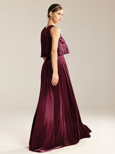 a woman in a long purple dress is looking back at the camera and she has her hand on her hip