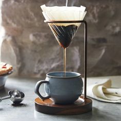 an espresso machine pours coffee into a cup on top of a wooden stand