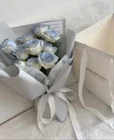 a bouquet of white roses sitting in a box next to an open card and envelope