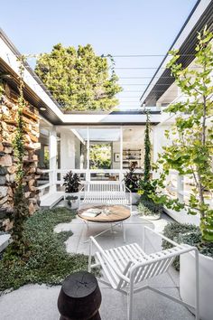 a white bench sitting in the middle of a patio next to a tree and bushes