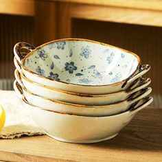 a stack of white bowls sitting on top of a wooden table next to a lemon