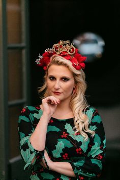 a woman wearing a tiara and looking at the camera with her hand on her chin