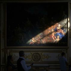 people are standing in front of a painting with light coming from it's window