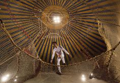 a man standing on top of a net in the middle of a room filled with ropes