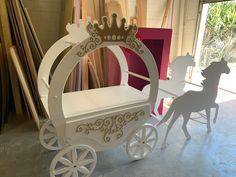 a white horse drawn carriage sitting in front of a window next to a pink box