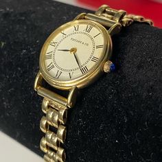 Vintage Tiffany & Co 14k Yellow Gold Quartz 20.5 Mm Watch. The Face Is An Off White Color And Has Black Roman Numerals, "Tiffany & Co." And "Swiss" Writing. There Is A Blue Shappire In The Crown Dial. There Is A Small Crack On The Face And Only Noticable When Upclose. Small Scuffs On The Gold From Wear. This Is Estimated To Be 1960-80’s And Is Amazing Condition For Its Age. It Works Great And A New Battery Was Installed 01/18/2024. I Would Suggest Measuring Your (Or Your Ladies) Wrist As The Band Is Short. It Is Right At 6 Inches Long To The Lock Position. There Is A Double Lock Latch On Both Sides Of The Clasp. Per A Verbal Appraisal Watch Is Estimated Price Range Of 4-5k. Please See All Classic Yellow Gold Watch For Gift, Timeless Yellow Gold Jewelry And Watches, Polished Finish, Timeless Polished Yellow Gold Jewelry, Timeless Yellow Gold Jewelry And Watches For Formal Occasions, Timeless Yellow Gold Jewelry With Polished Finish, Classic Yellow Gold Round Jewelry And Watches, 14k Gold Round Watches For Formal Occasions, Elegant Gold Jewelry And Watches For Formal Occasions, 14k Yellow Gold Watch For Formal Occasions