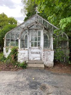 an old, run down building is surrounded by greenery and trees in the background