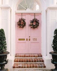 a pink door with two wreaths on it