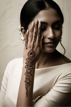 a woman holding her hands up to her face with hendi tattoos on the arm