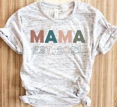 a white shirt with the word mama printed on it, sitting on top of a wooden floor