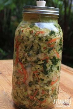 a jar filled with vegetables sitting on top of a wooden table