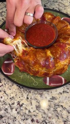 a person dipping sauce onto a pizza on a plate