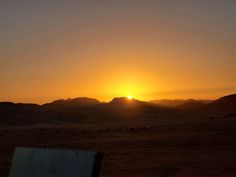 the sun is setting over mountains in the desert