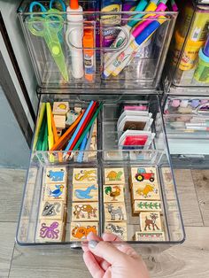 someone is holding their hand in front of the drawer full of crafting supplies and crafts