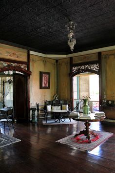 a living room filled with furniture and a chandelier hanging from the ceiling over a wooden floor