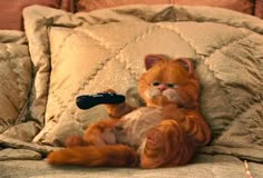 an orange cat sitting on top of a couch with a remote control in it's paws