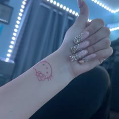 a woman's hand with a hello kitty tattoo on it, in front of a mirror