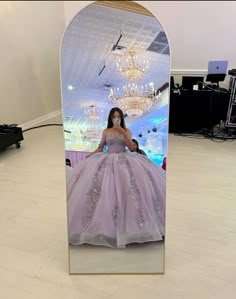 a woman in a ball gown is reflected in a mirror with chandelier hanging from the ceiling