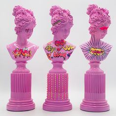 three pink plastic busturines with pop art designs on their heads and hair in the shape of women's heads