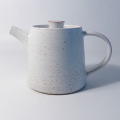 a white tea pot with gold speckles on the outside and inside, sitting in front of a white background