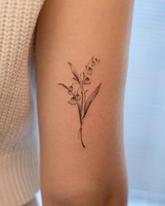 a woman's arm with a small flower tattoo on the left side of her body