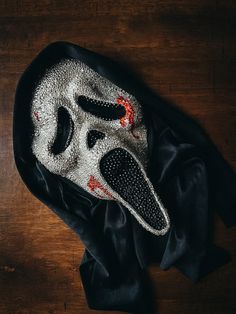 a black and white mask sitting on top of a wooden table next to a cloth