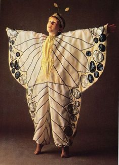 a woman in a butterfly costume standing with her arms spread out to the side and eyes closed