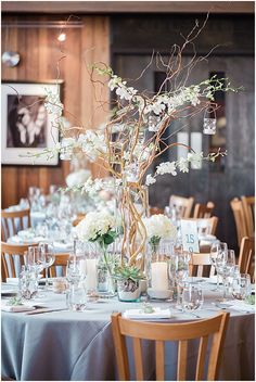 the centerpieces are arranged in vases with white flowers and greenery on them