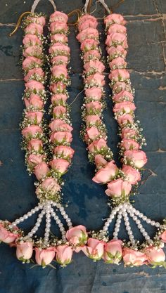 three necklaces with pink roses and pearls on them, sitting next to each other