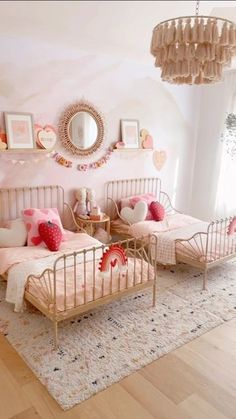 two twin beds in a pink bedroom with hearts on the wall above them and a chandelier hanging from the ceiling