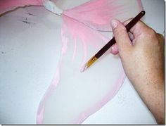 a person holding a pencil in their left hand while painting a pink flower with white paint