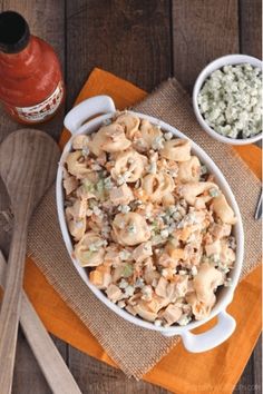 a bowl filled with pasta next to two spoons and a bottle of ketchup