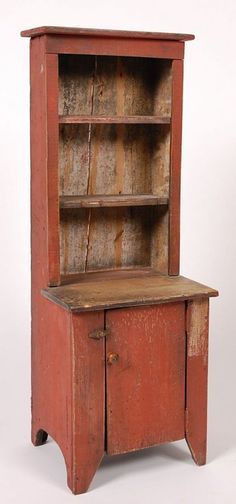 an old red wooden cabinet with shelves and cupboard doors on one side, the door is open