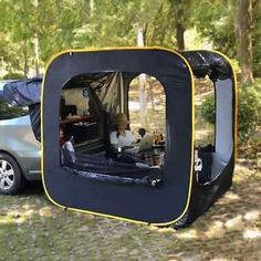 a car is parked next to a tent with a dog in it and the back door open