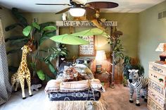 a living room with zebras and giraffe statues on the floor, in front of a ceiling fan