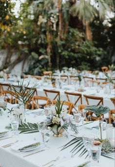 an outdoor wedding reception set up with white tablecloths and greenery on the tables