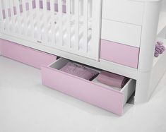 a white crib with pink drawers in the middle and a baby's bed next to it